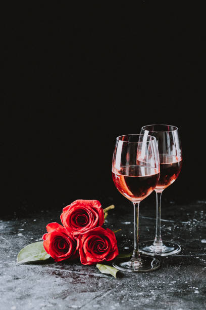 zwei gläser wein rose wein für ehe valentinstag liebe geburtstagsfeier auf dunklem hintergrund - cluster verlobungsringe stock-fotos und bilder