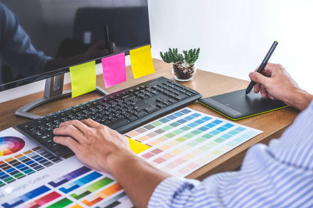 istock Image of male creative graphic designer working on color selection and drawing on graphics tablet at workplace with work tools and accessories in workspace 1125391444