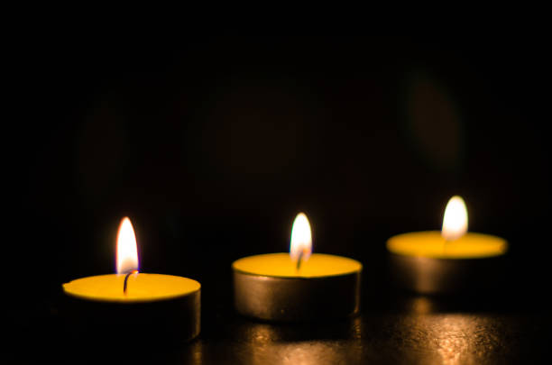 istock Three burning candles isolated on black background. 1125394122