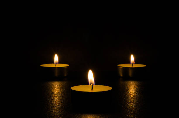 istock Three burning candles isolated on black background. 1125394204