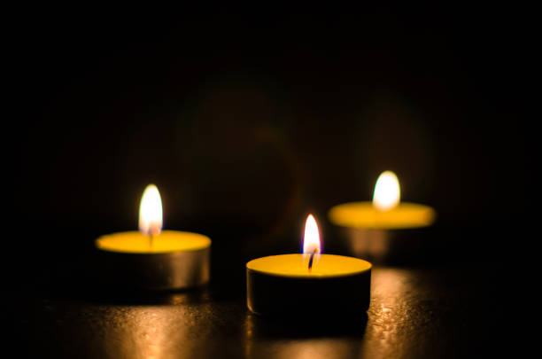 istock Three burning candles isolated on black background. 1125394259