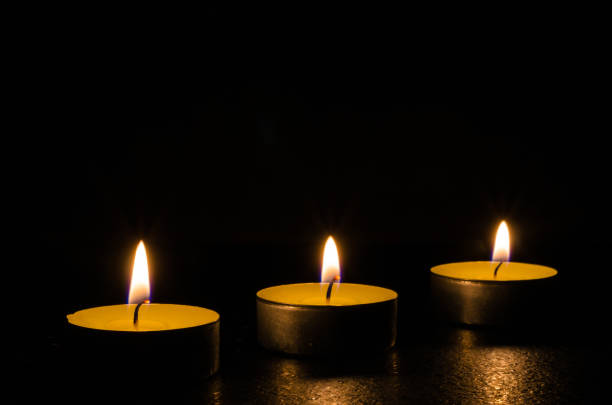 istock Three burning candles isolated on black background. 1125394427