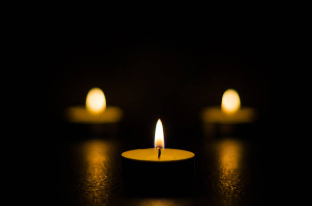 istock Three burning candles isolated on black background. 1125394534