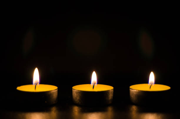 istock Three burning candles isolated on black background. 1125394546