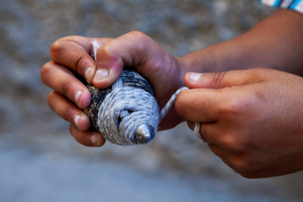 A boy rolling the string in a wooden spinning top on the road. Old Turkish traditional toy.