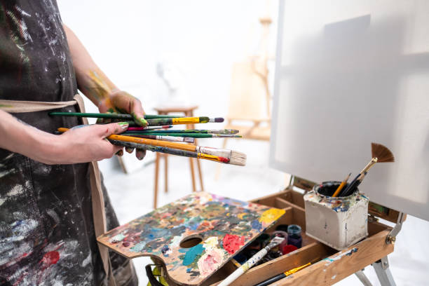 istock Young beautiful girl painter in a white studio draws on an easel on canvas. 1125404533