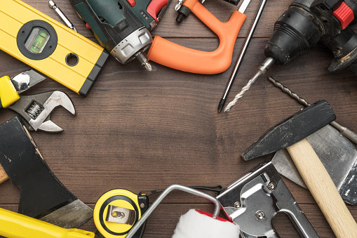 different construction tools on wooden background with copy space. top view of diy construction tools on the brown table. close-up of many reparing tools making up a frame