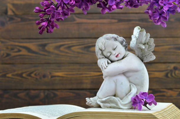 istock Angel and lilac flower on old book 1125415758