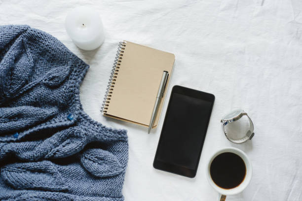 istock Blue knitted sweater, coffee , notebook, candle, smart phone on bed, top view. 1125421071