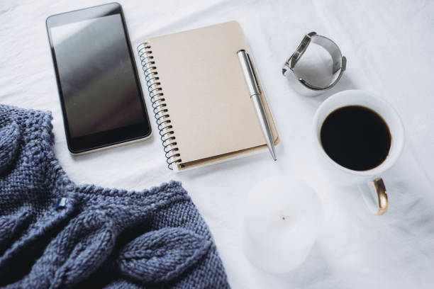 istock Blue knitted sweater, coffee , notebook, candle, smart phone on bed, top view. 1125422544