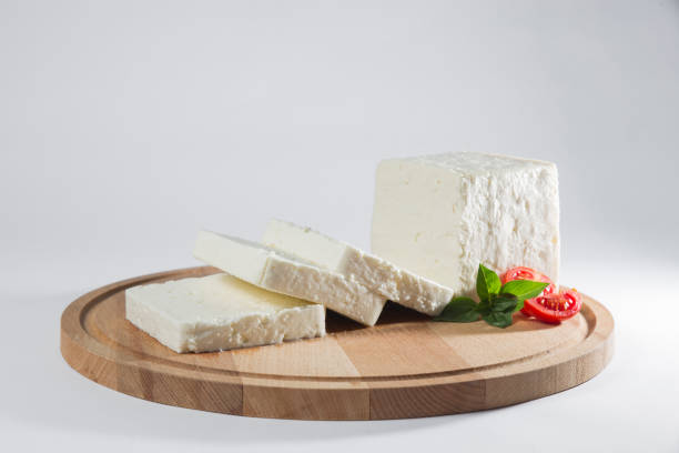 istock White cheese with some garnitures such as lettuce, cherry tomato slice and basil on a wooden plate, white background 1125422732