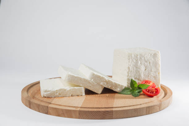 istock White cheese with some garnitures such as lettuce, cherry tomato slice and basil on a wooden plate, white background 1125422797