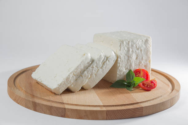 istock White cheese with some garnitures such as lettuce, cherry tomato slice and basil on a wooden plate, white background 1125423803