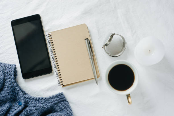 istock Blue knitted sweater, coffee , notebook, candle, smart phone on bed, top view. 1125424818