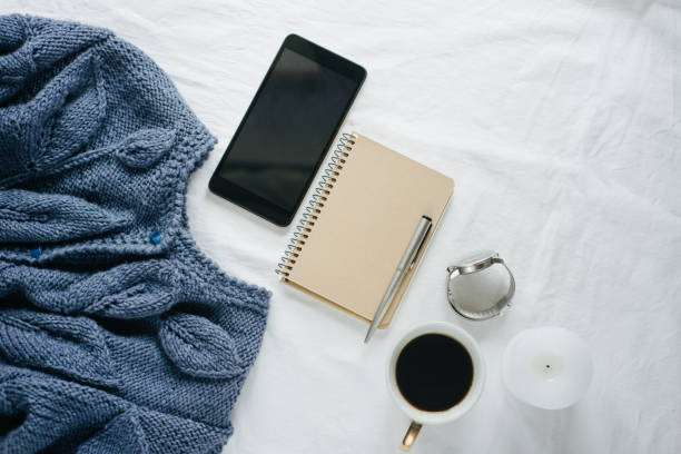 istock Blue knitted sweater, coffee , notebook, candle, smart phone on bed, top view. 1125424821