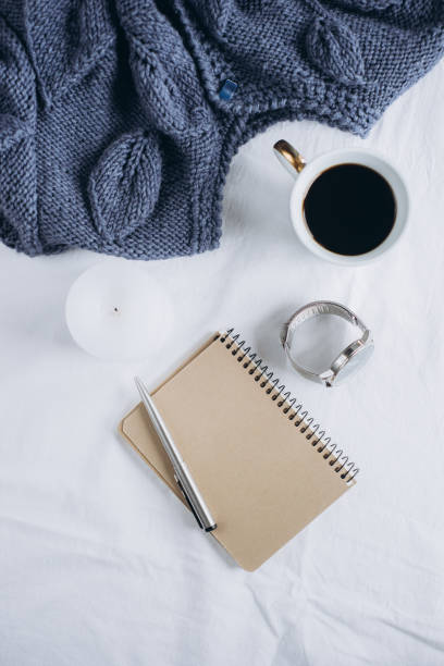 istock Cup coffee , blue knitted sweater, notebook with pen, clock, candle on bed, top view. 1125424917