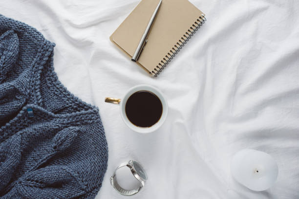 istock Cup coffee , blue knitted sweater, notebook with pen, clock, candle on bed, top view. 1125429792