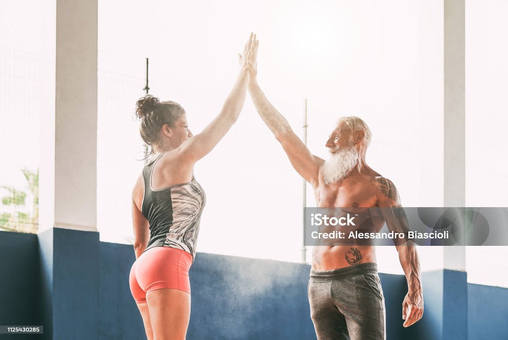 Fitness couple stacking hands in gym wellness club - Happy athletes motivating each other - Concept of people training, fit, empowering and bodybuilding lifestyle Senior Adult Stock Photo