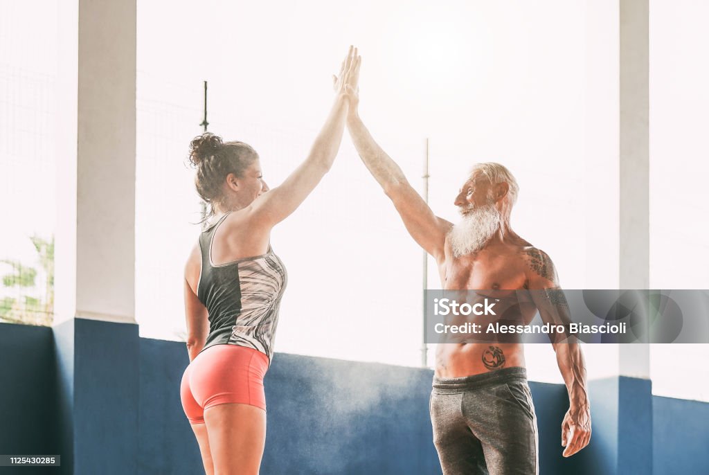 Empilhamento de casal de aptidão mãos no clube de bem-estar do ginásio - felizes atletas motivar uns aos outros - conceito de pessoas que treinam, caber, capacitando e bodybuilding lifestyle - Foto de stock de Terceira idade royalty-free