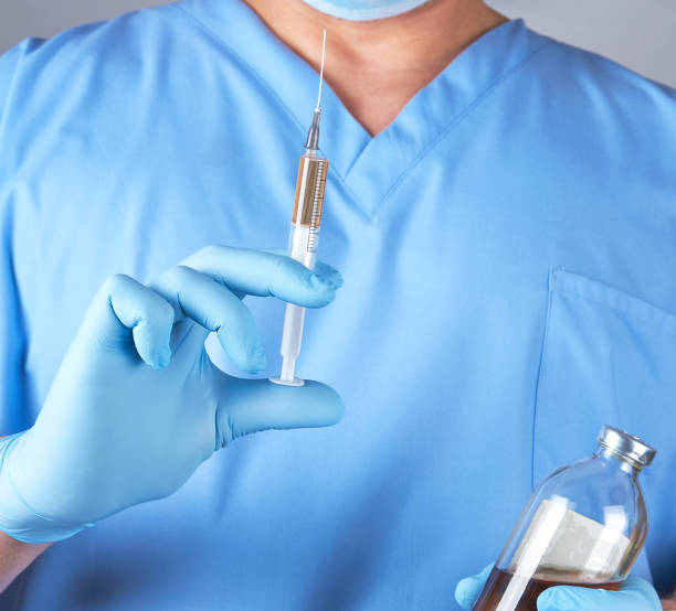 istock male doctor in blue uniform holding a syringe 1125431423