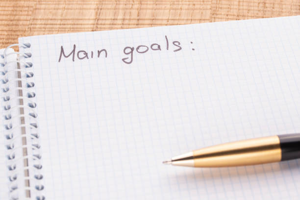 istock Top view workplace notebook and pen on wood table background, retro effect. The inscription - main oals. 1125434790