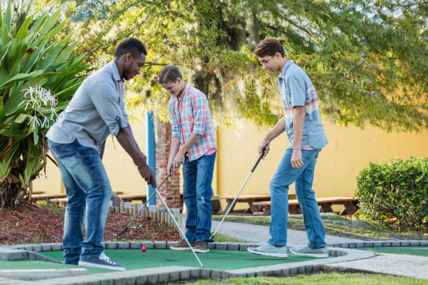 istock Three multi-ethnic teenage boys playing miniature golf 1125443966