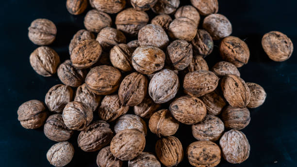 istock walnuts macro photography, a bunch of nuts with a great texture on black surface and dark background 1125444927