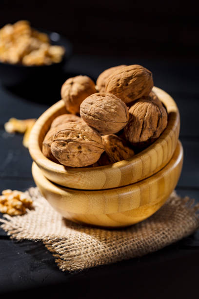 istock Nuts with shell in wooden bowls on slate background