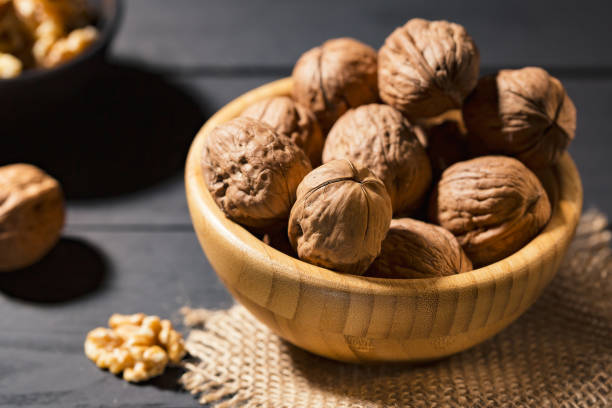 istock Nuts with shell in wooden bowls on slate background