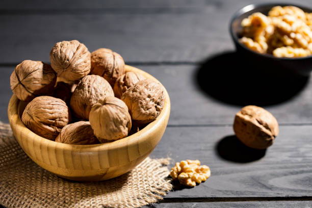 istock Nuts with shell in wooden bowls on slate background