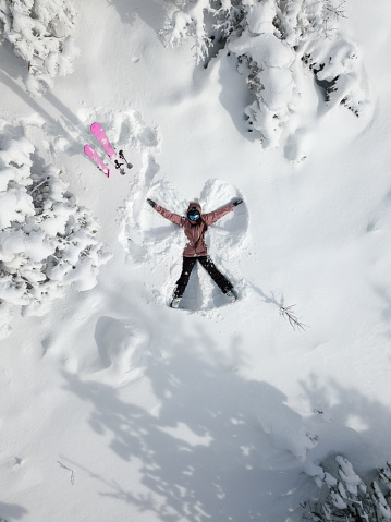 Young woman skier making snow angel from above