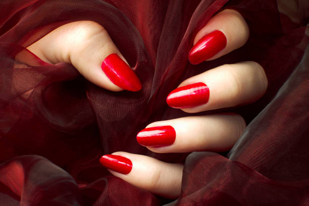 red nails manicure Female hand with sensual red nails on dark red background, manicure and nail care concept. red nail polish stock pictures, royalty-free photos & images