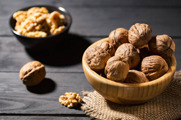 istock Nuts with shell in wooden bowls on slate background