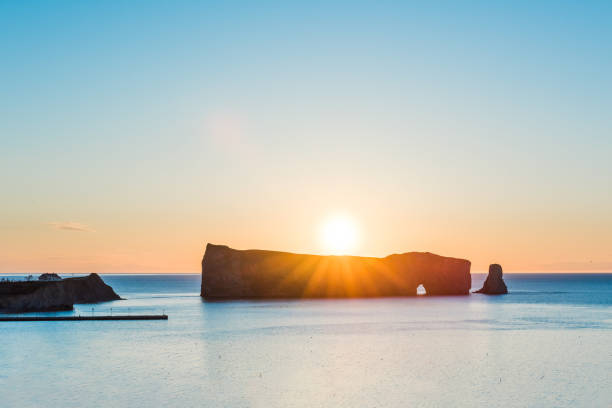 roche de rocher percé en gaspésie, au québec, gaspesie région agrandi au lever du jour avec le soleil derrière sunburst et rayons - lighthouse lighting equipment reflection rock photos et images de collection