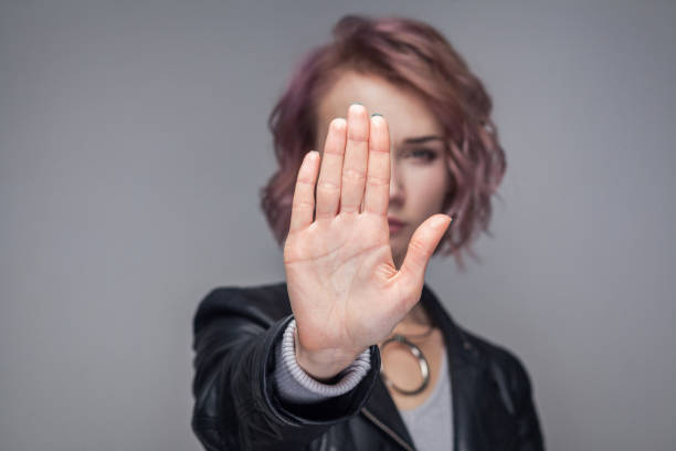 arrêter. portrait de grave belle fille avec les cheveux courts en blouson de cuir noir de style décontracté debout dans le geste d’arrêt et regardant la caméra. - bad habit fear emotional stress women photos et images de collection