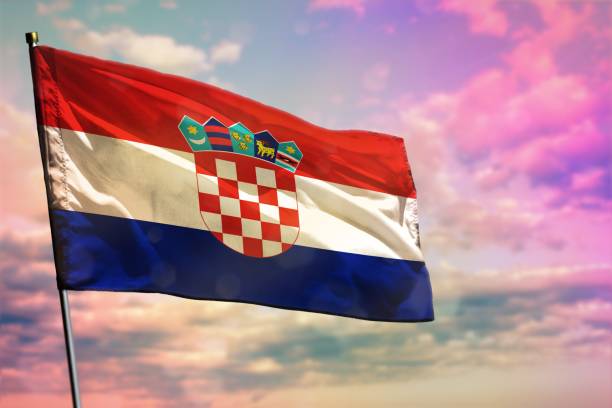 istock Fluttering Croatia flag on colorful cloudy sky background. Prosperity concept. 1125465577