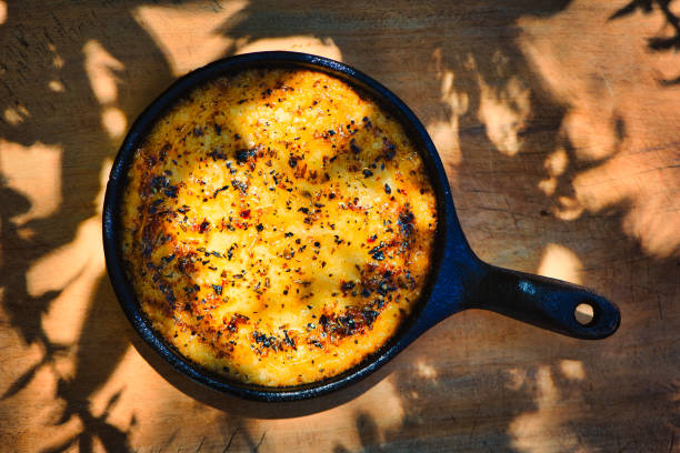 Delicious Argentinian Provolone Yarn Cheese (Provoleta) that was cooked in a cast iron skillet over the embers presented on an old wooden board. stock photo