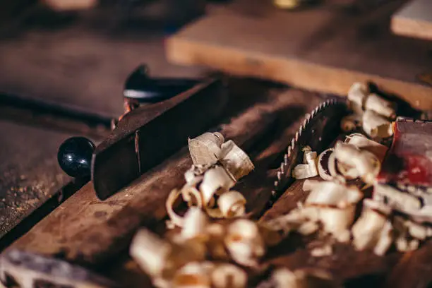 Wood chips (shavings) on wooden surface, antique plane on the carpenter worktable.