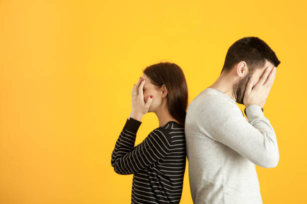 istock Side profile of a young couple standing back to back, hiding faces with hands 1125473233