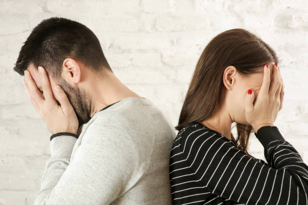 istock Side profile of a young couple standing back to back, hiding faces with hands 1125475216