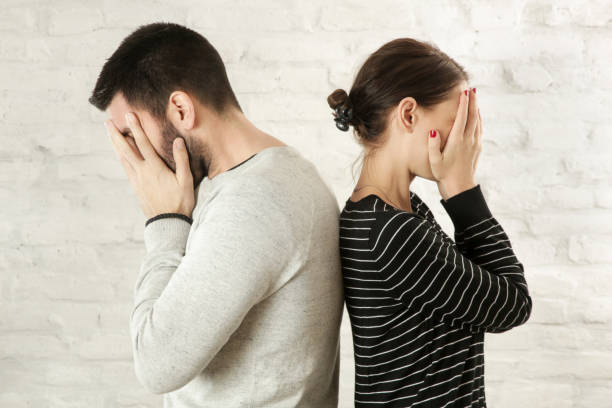 istock Side profile of a young couple standing back to back, hiding faces with hands 1125475323