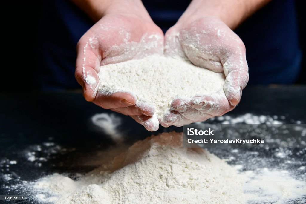パンは、小麦粉の一握りを保持します。 - ドウ生地のロイヤリティフリーストックフォト