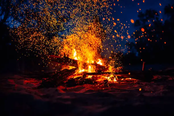 Summer beach bonfire with sparks flying around and flames blazing