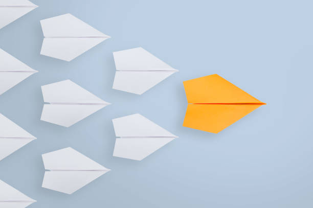 istock Leadership concepts with orange paper airplane leading among white 1125482202