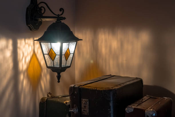 Ancient lamp hangs on a wall. Three old rusty suitcases are next to it