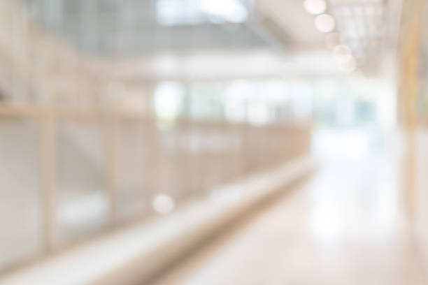 istock Corridor in school or office building blur background with blurry interior view empty hall way, glass curtain wall and floor with exterior light illumination 1125486797