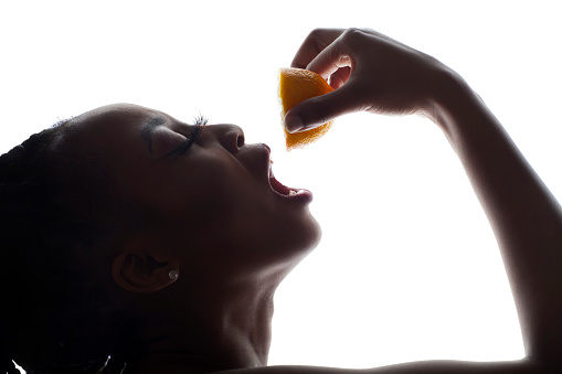 Silhouette of a young African woman squeezing a lemon