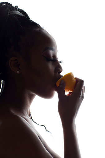 Silhouette of a young African woman licking a lemon