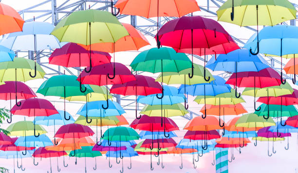 sombrillas de colores colgaron en el cielo soleado. - rainbow umbrella descriptive color multi colored fotografías e imágenes de stock