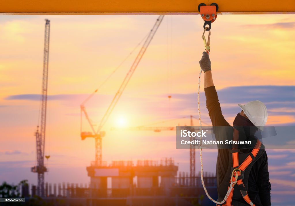 Construction worker wearing safety harness. Construction worker wearing safety harness and safety line working high place at industrial. Falling Stock Photo